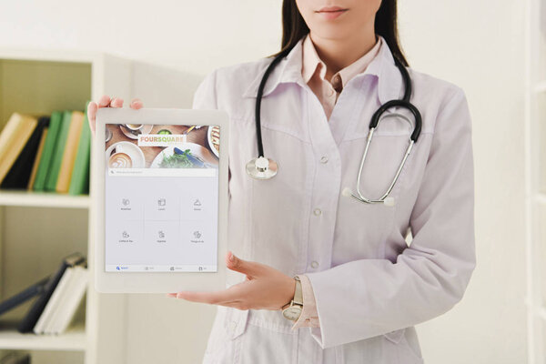 cropped view of doctor presenting digital tablet with foursquare appliance
