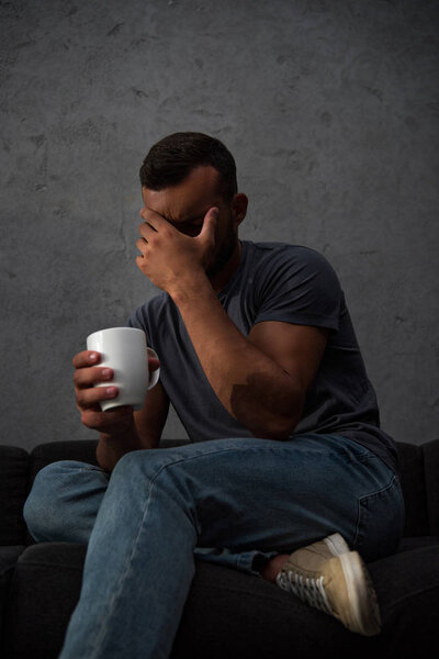 depressed crying man holding cup of coffee sitting at home