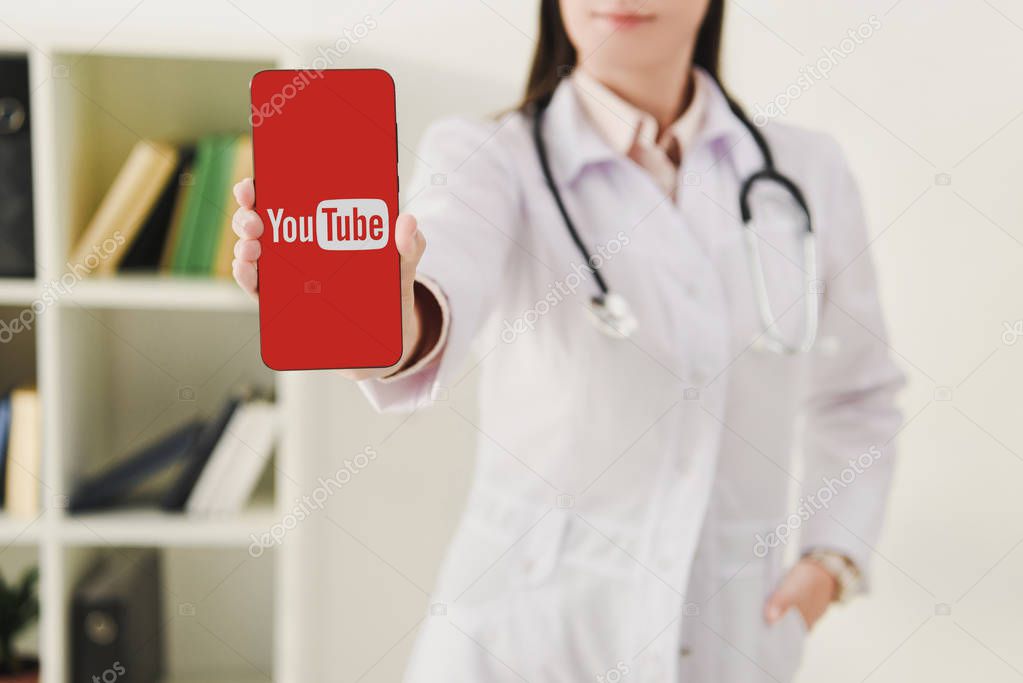 Cropped view of doctor presenting smartphone with youtube logo