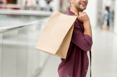 Genç adam alışveriş merkezi kağıt torba tutarak görüntü kırpılmış 