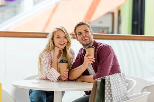 Gelukkige Paar Met Winkelen Bugs Aan Tafel Met Wegwerp Kopjes — Gratis stockfoto