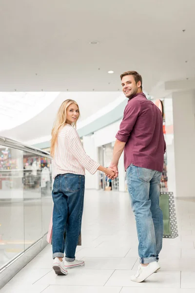 Jonge Gelukkige Paar Van Shoppers Met Papieren Zakken Camera Kijken — Gratis stockfoto