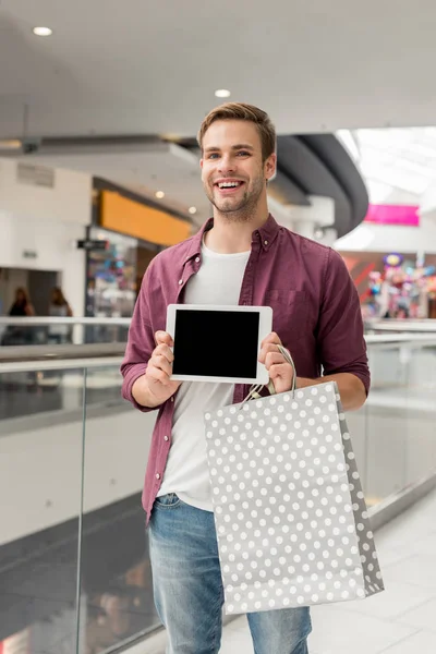 Pemuda Tampan Dengan Tas Belanja Menunjukkan Tablet Digital Dengan Layar — Foto Stok Gratis