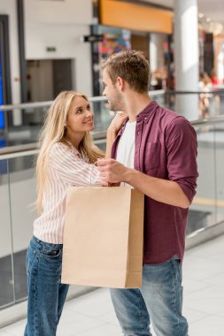 alışveriş alışveriş merkezinde birbirine bakarak çantası ile genç bir çift gülümseyen 