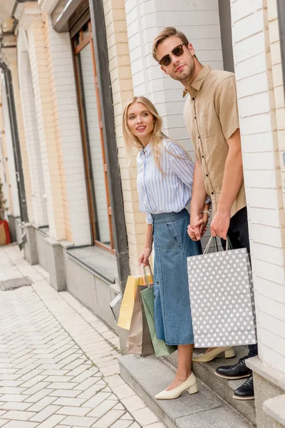 若いカップルが都市の通りを離れて見て買い物袋 — ストック写真