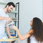 Beau jeune homme souriant versant du café à belle petite amie dans la chambre