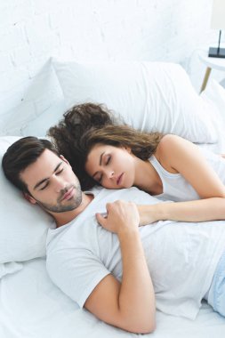 genç çiftin birlikte yatakta uyurken el ele tutuşarak yüksek açılı görünüş