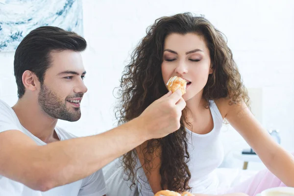 Smiling Young Man Feeding Beautiful Girlfriend Croissant Breakfast Bedroom — Stock Photo, Image