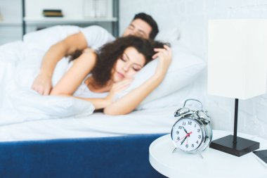 çalar saat ve yatakta uyuyan güzel genç çift yakından görmek 