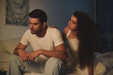Genç Kadın pijama yatağa gece, ilişki zorluklar kavramı oturan üzgün erkek arıyor