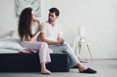 Genç çift pijama yatağa dizüstü bilgisayar kullanarak