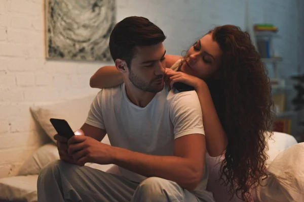 Ελκυστική Νεαρή Γυναίκα Ψάχνει Στο Φίλο Χρησιμοποιώντας Smartphone Στο Κρεβάτι — Φωτογραφία Αρχείου