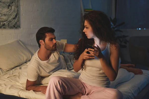 Joven Molesto Mirando Novia Usando Teléfono Inteligente Por Noche Concepto —  Fotos de Stock