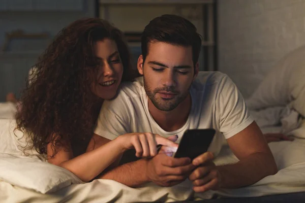 Smiling Young Couple Lying Bed Using Smartphone — Free Stock Photo