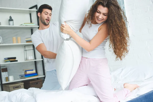 Gelukkige Jonge Paar Pyjama Met Plezier Vechten Met Kussens Bed — Gratis stockfoto