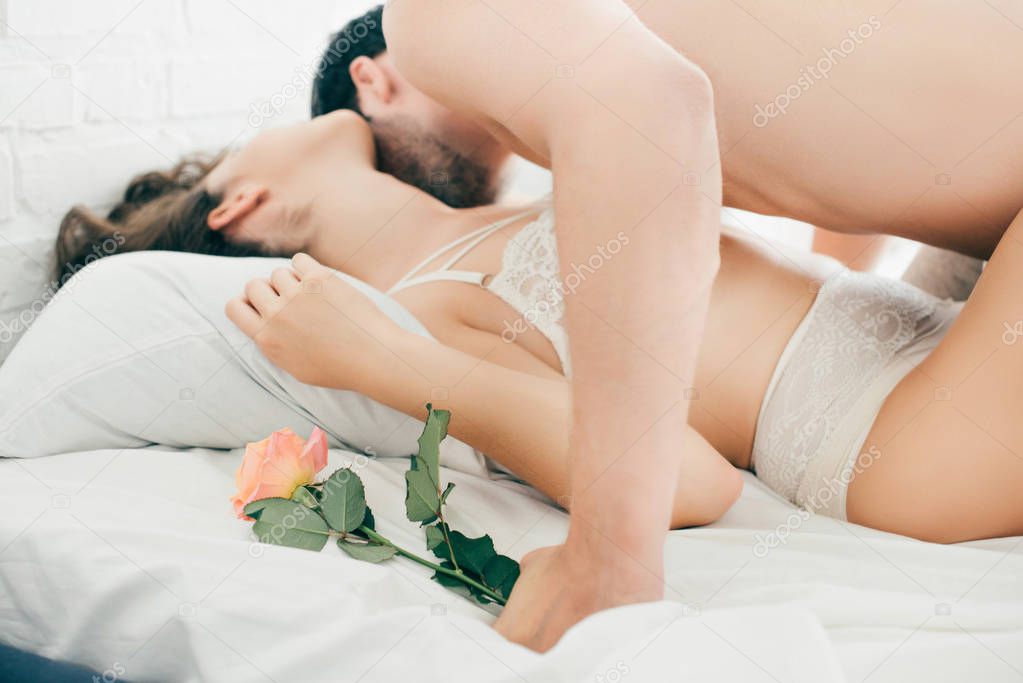 man holding rose flower and kissing sexy girlfriend in bed