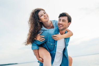 eğleniyor ve denize yakın piggybacking mutlu çift 