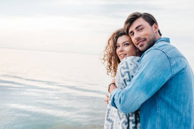 yakışıklı adam kucaklama gülümseyen kız battaniye nea denizde sarılmış