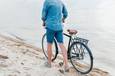 Bisiklet ile Kum Plajı üzerinde yürüyen adam görünümünü kırpılmış