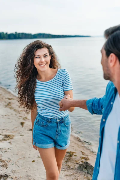 güzel çift tutuşup gülümseyen ve deniz kenarında plajda yürüyüş 