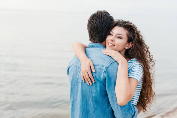 beautiful happy couple embracing near sea 