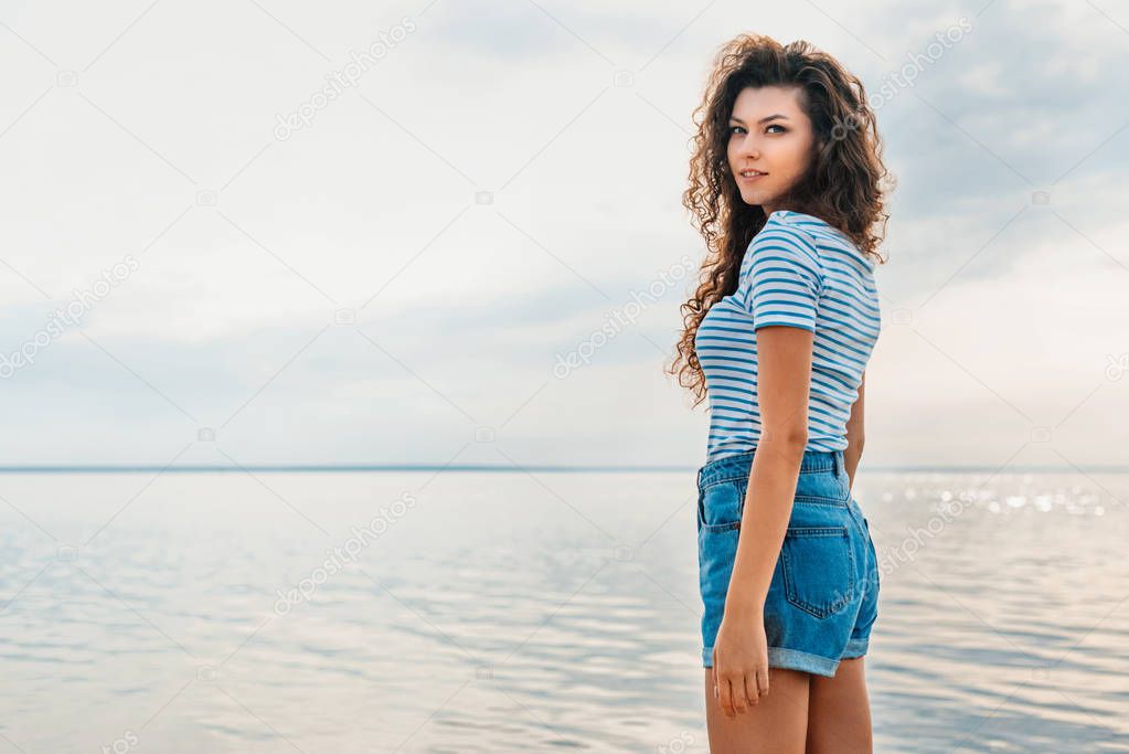 attractive curly girl in casual clothes posing near the seas 