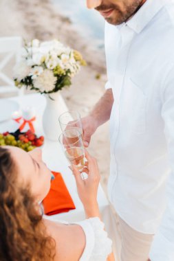 İki şampanya bardağı ile romantik tarih sırasında sahil üzerinde tungur görünümünü kırpılmış