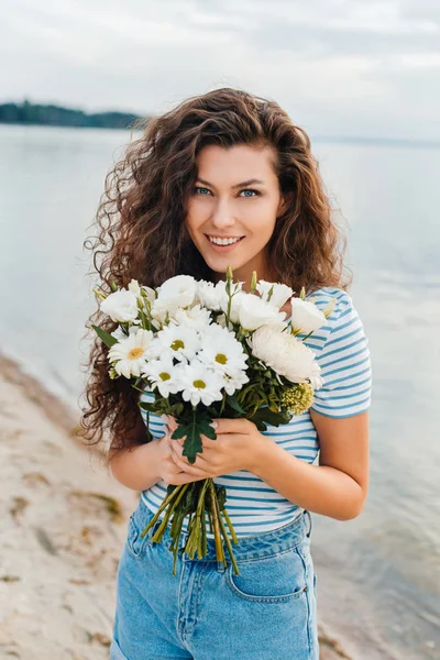 Atrakcyjna Kobieta Szczęśliwa Pozować Bukietem Kwiatów Plaży — Darmowe zdjęcie stockowe