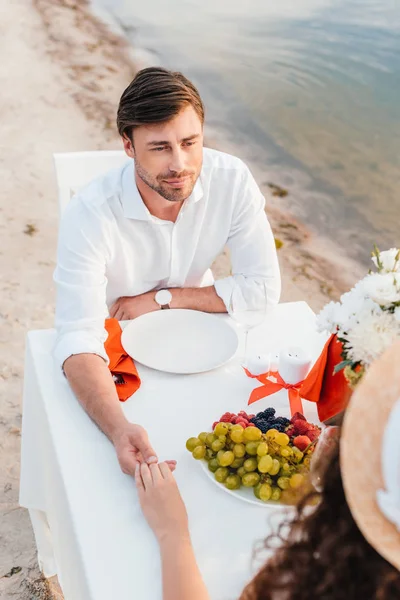海岸でロマンチックなデートで手を繋いでいる美しいカップル  — 無料ストックフォト