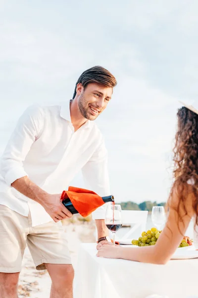 Uomo Sorridente Versando Vino Rosso Nel Bicchiere Fidanzata Appuntamento Romantico — Foto stock gratuita