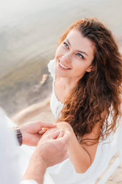 partial view of man wearing proposal ring on womans finger  