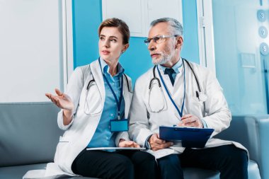 kadın doktor dijital tablet el ile Divan hastane koridorda erkek meslektaşı işaret ile 