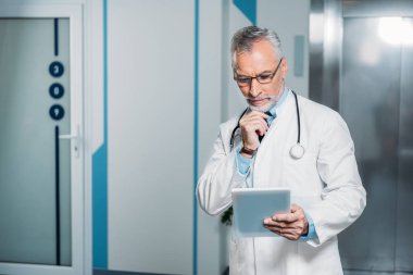 olgun erkek doktor stetoskop üzerinden dijital tablet hastanede tutan boyun ile 