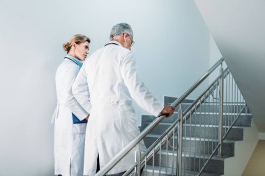 Erkek ve kadın doktorlar hastanede merdiven üzerinde yürüyen dikiz 