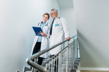 kadın doktor gösteren hastane merdiven üzerinde erkek meslektaşı panoya 