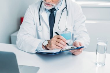 Pano'da yazma ve office içinde laptop bakarak erkek doktor kısmi görünümünü 