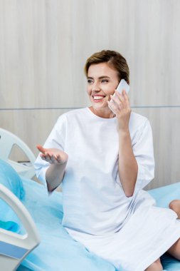 mutlu kadın hasta tarafından el eller ve hastane odasında Smartphone cep telefonu ile konuşmak