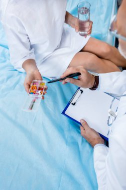 Bayan hasta hastane odasında haplara işaret boyun üzerinden stetoskop ile orta yaşlı erkek doktor görüntü kırpılmış 