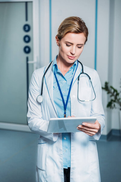 adult female doctor with stethoscope over neck using digital tablet in hospital 