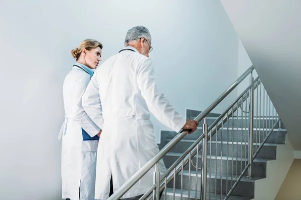 在医院楼梯上行走的男女医生的后视 — 图库照片