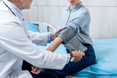 erkek doktor hastane odasında tonometer tarafından bayan hasta basınç ölçme kısmi görünümünü