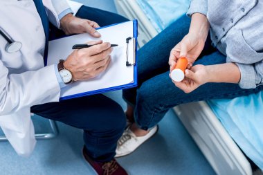 olgun erkek doktor hastane odasında haplarla Pano bayan hasta yakınındaki yazılı resim kırpılmış