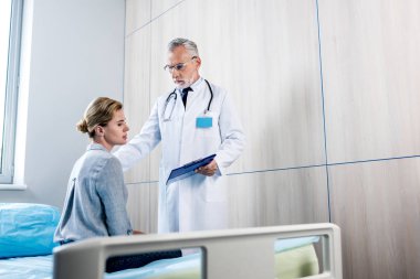 olgun erkek doktor hastane odasında Bayan hasta tezahürat Pano ile