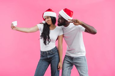 barış, pembe arka plan izole işareti yapıyor erkek ördek yüz ve alma selfie Smartphone cep telefonu ile yapıyor Noel şapkalı Afrika kökenli Amerikalı kadın 