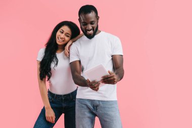 genç Afro-Amerikan çift dijital tablet, pembe arka plan izole kullanma 