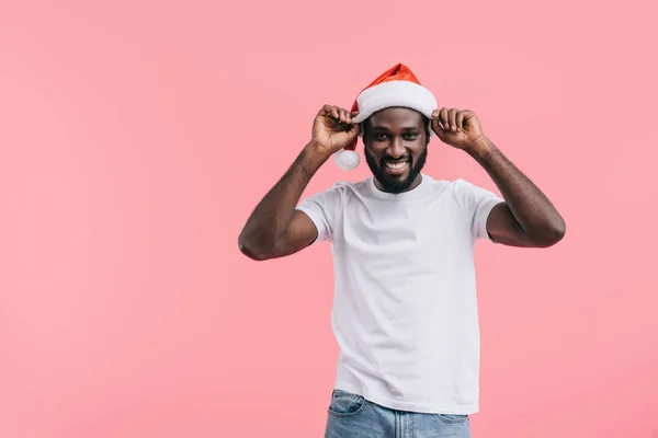 Lächelnder Afrikanisch Amerikanischer Mann Setzt Weihnachtsmütze Isoliert Auf Rosa Hintergrund — Stockfoto