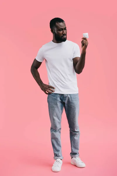 ピンクの背景に分離されたコンドームの若いアフリカ系アメリカ人 — ストック写真
