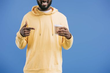 Afrika kökenli Amerikalı gencin parmak üzerinde mavi arka plan izole tek kullanımlık kahve Kupası'nda tarafından işaret kısmi görünümü