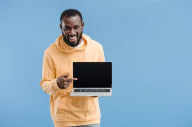boş ekran üzerinde mavi arka plan izole ile parmak laptop tarafından işaret genç Afro-Amerikan adam gülüyor