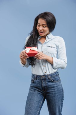 hediye kutusu üzerinde mavi arka plan izole tutan gülümseyen şık Afrikalı-Amerikalı kadın 